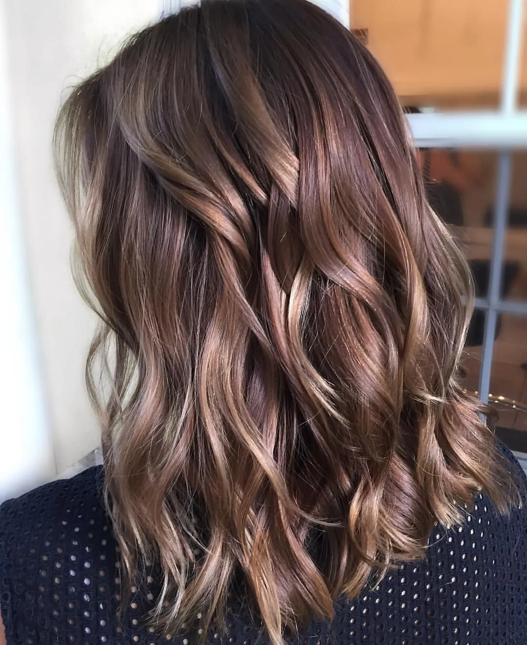 Процесс профессионального колорирования волос в салоне: мастер наносит краску на пряди с помощью кисти