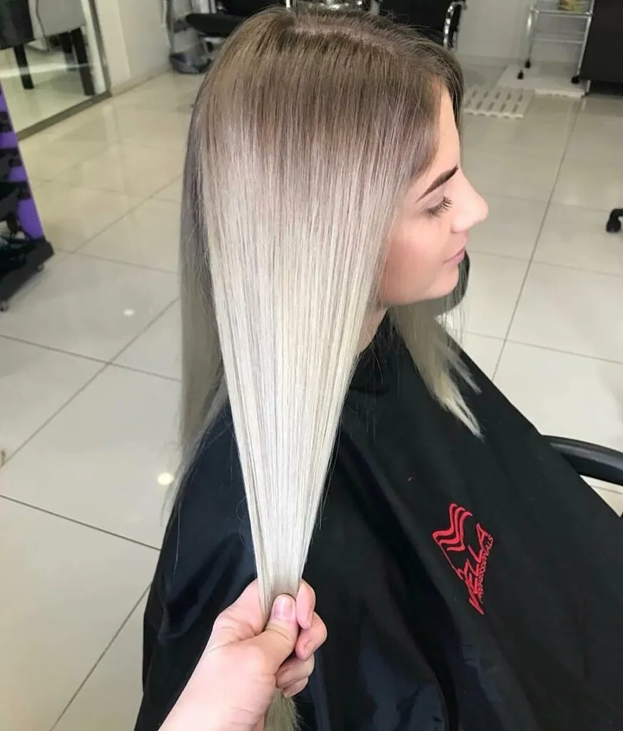 Процесс профессионального окрашивания волос в парикмахерской: мастер наносит краску на пряди