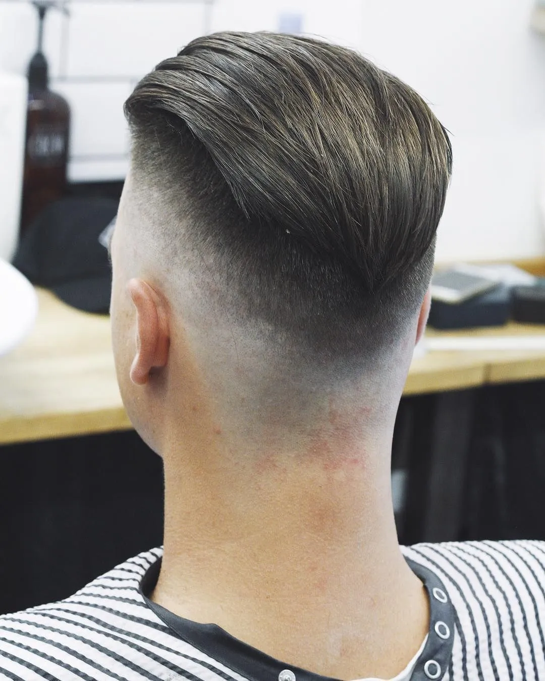 Стильная мужская стрижка андеркат с четким контуром и укладкой волос на макушке