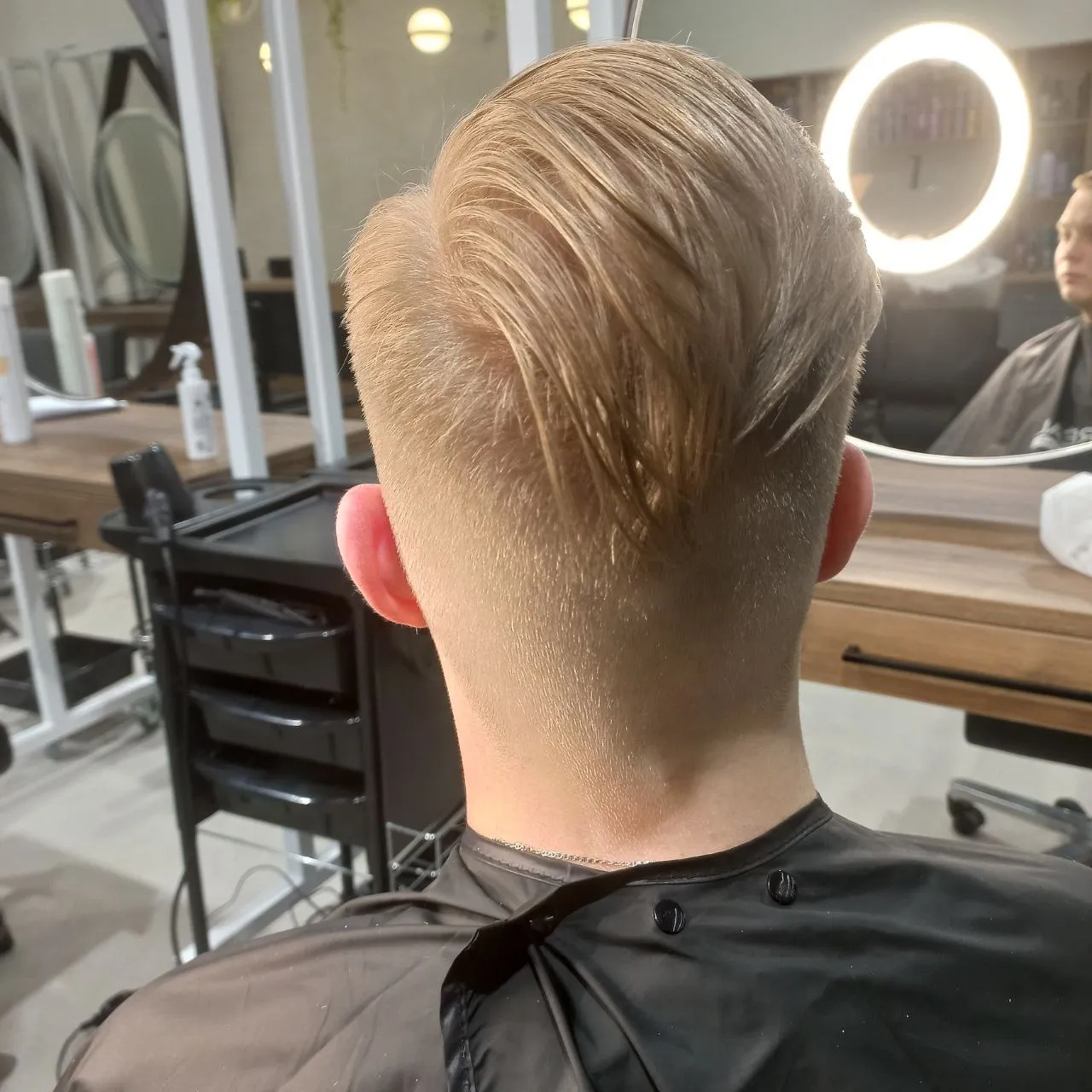 Стилист подбирает женскую стрижку в салоне красоты с учетом типа лица и структуры волос