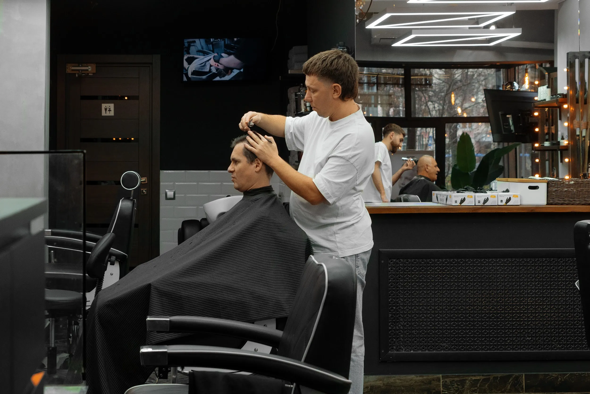Мастерская мужская стрижка ножницами в салоне Процесс выполнения мужской стрижки ножницами в профессиональном салоне, мастер создает текстуру и форму